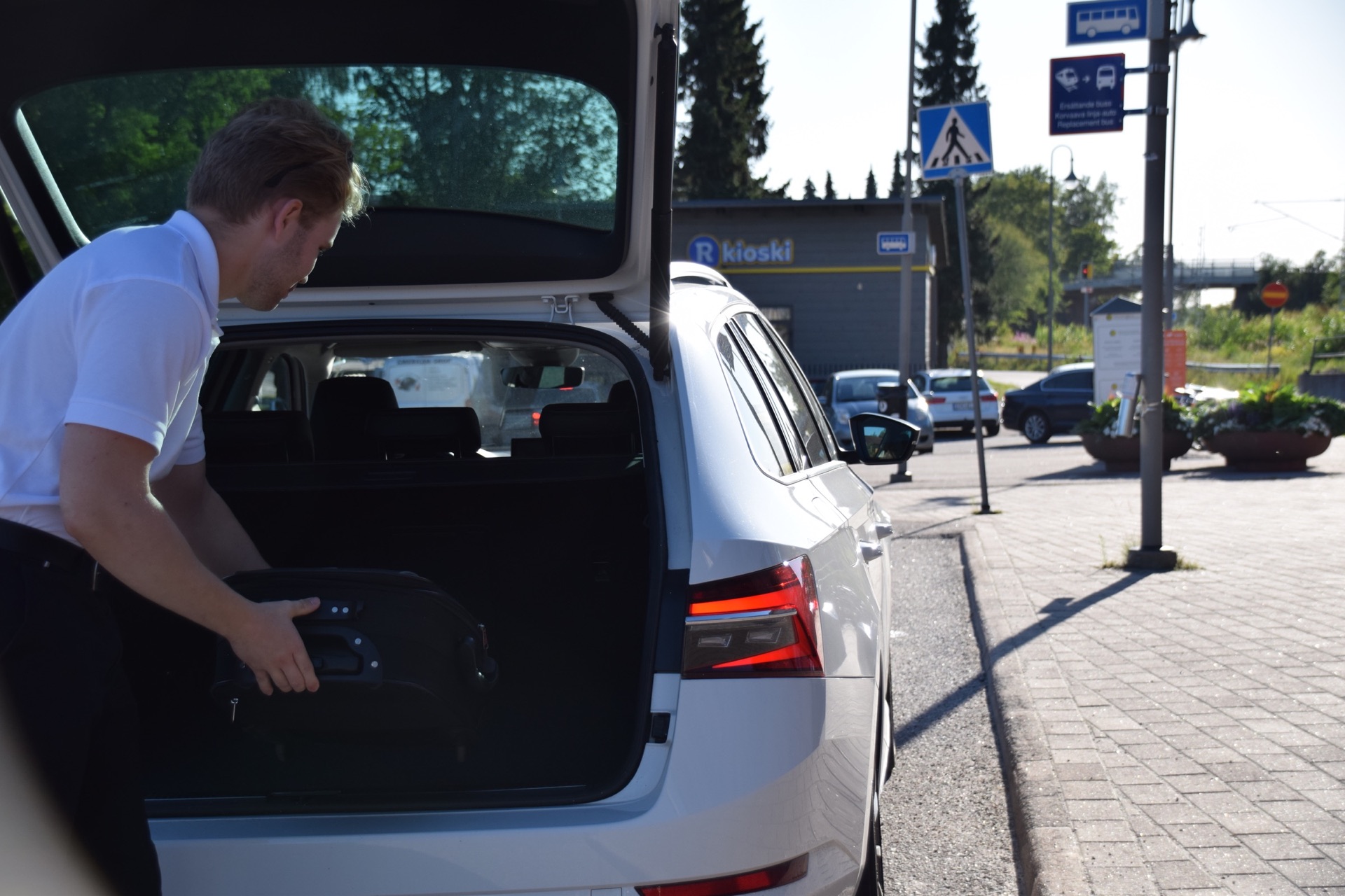 Chaufför lastar bagage i en Taxi Nylund-bil